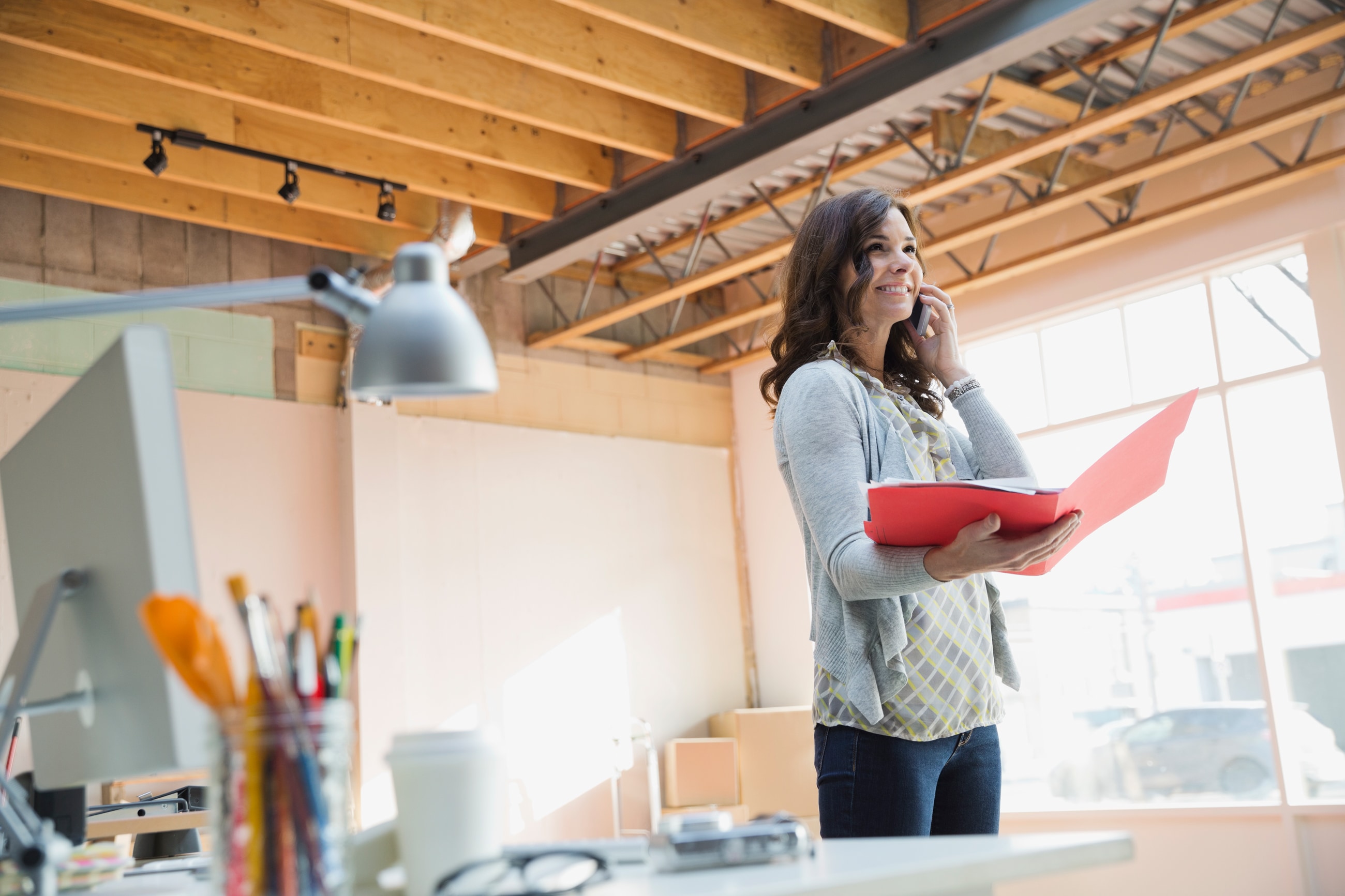 Woman standing in a bright room holding a folder