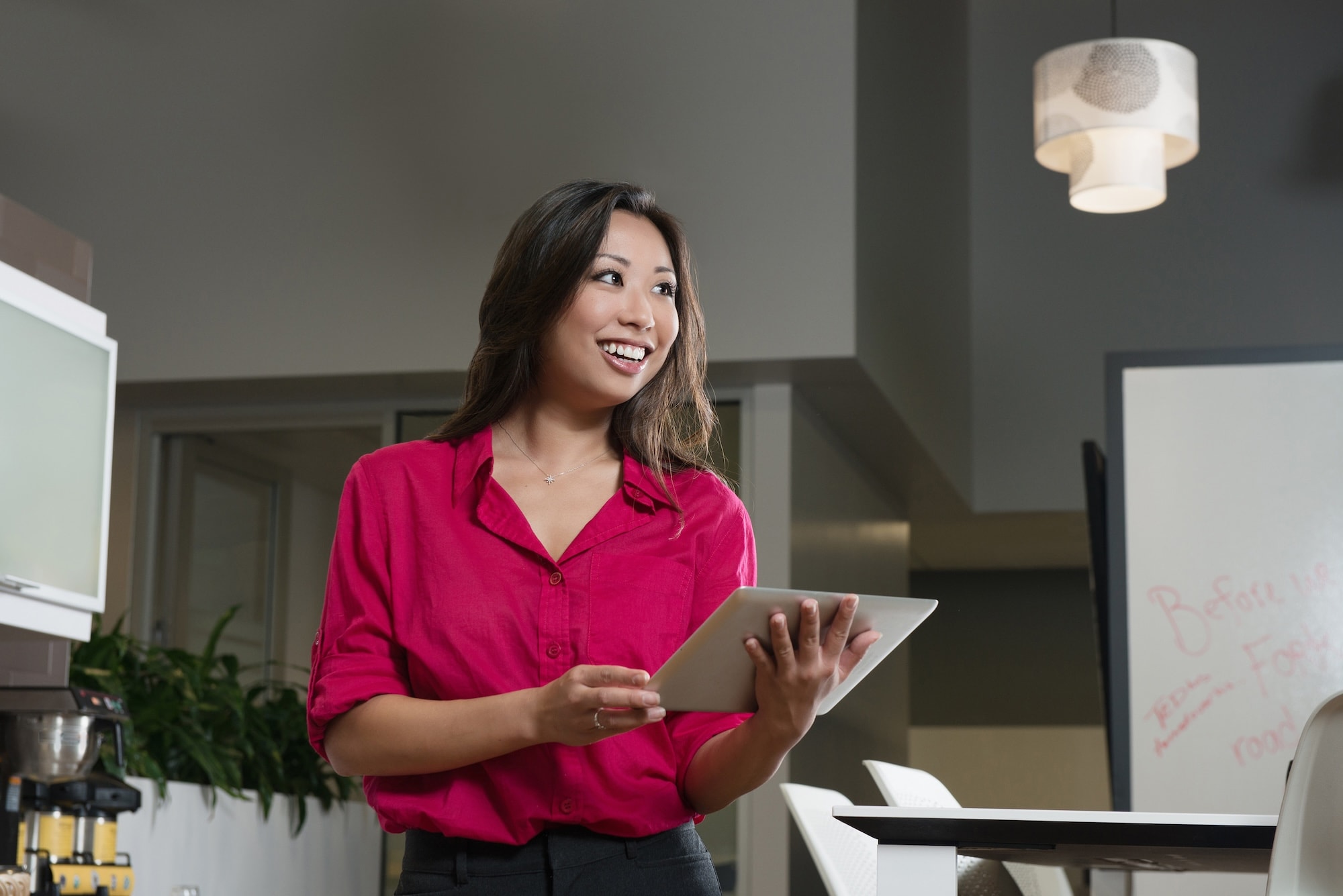 Woman in pink dress shirt holding tablet