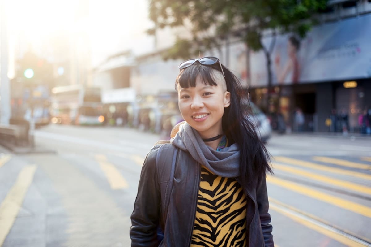 Asian woman with sunglasses and tiger-print shirt smiles at camera