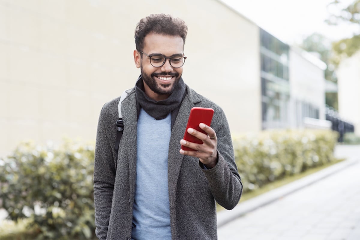 Man wearing backpack and glasses using phone