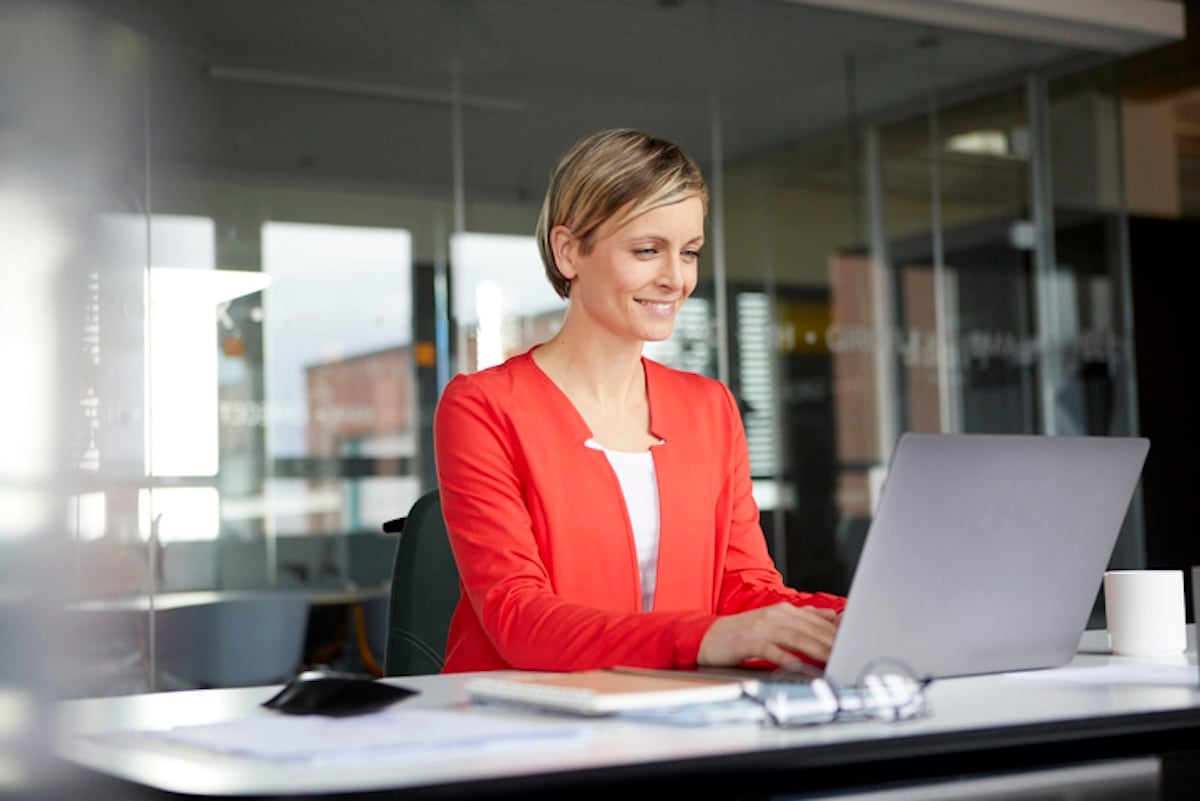 Woman in red blazer working on laptop