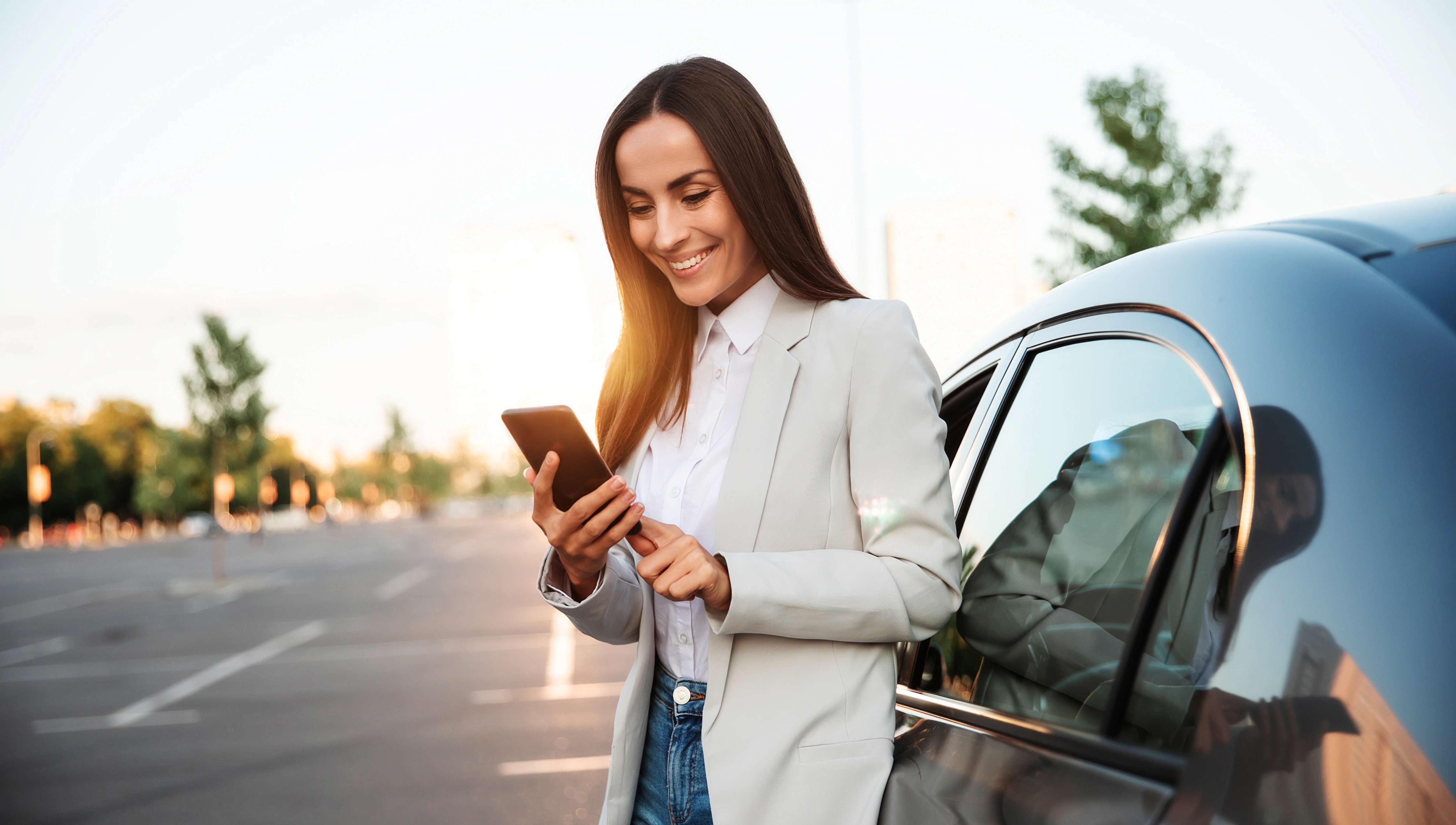 Woman on phone leaning against car