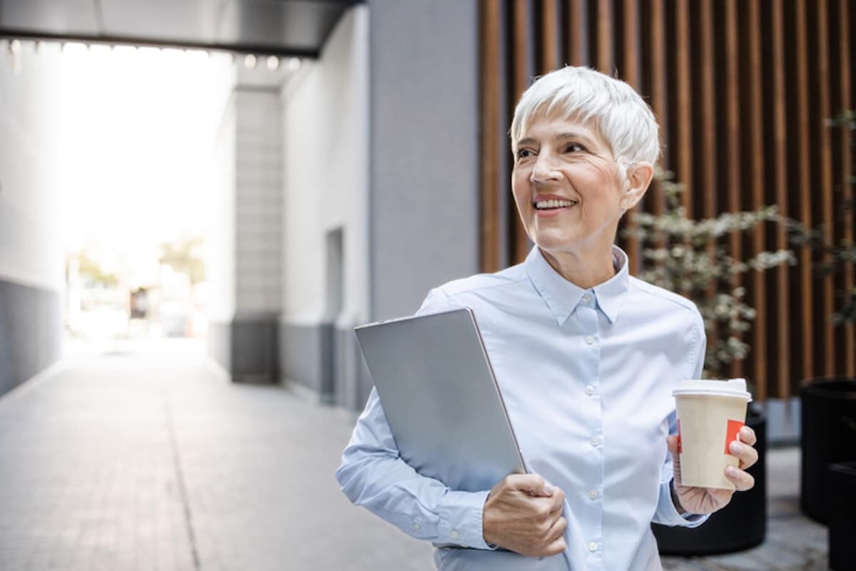 Short-haired woman carrying laptop and coffee cup