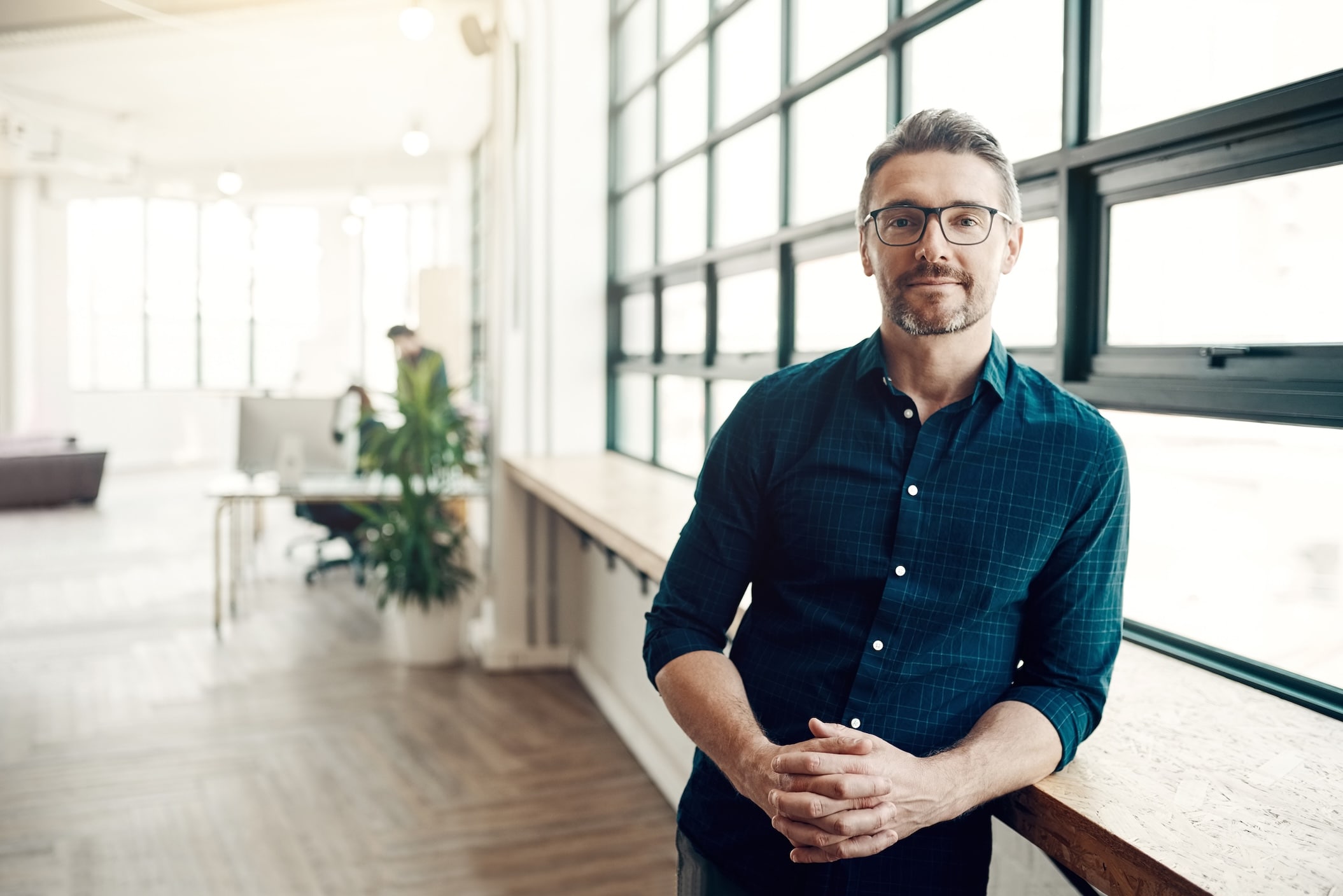 Man wearing eyeglasses leaning against counter