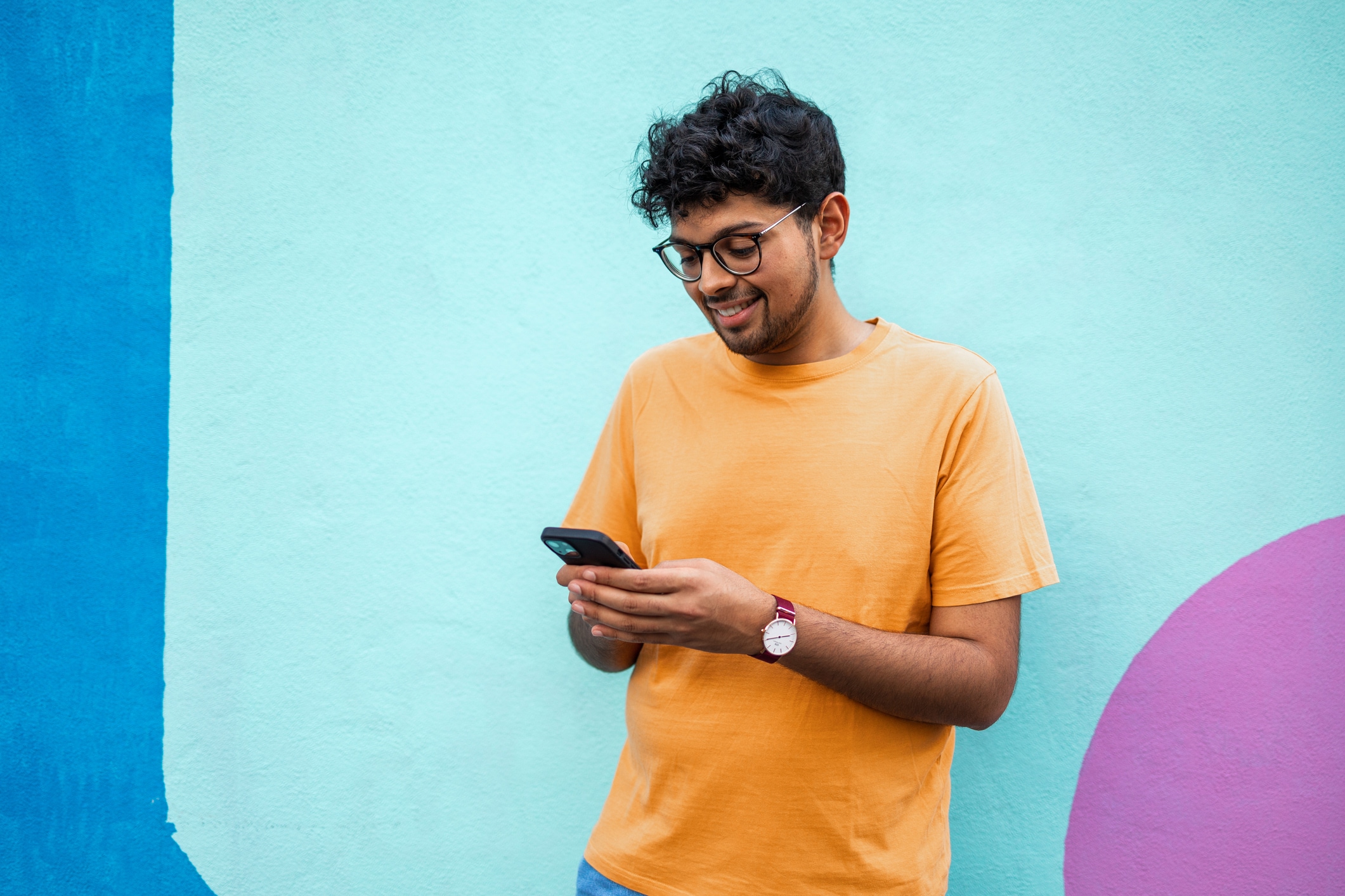 Man smiles at phone against colourful background