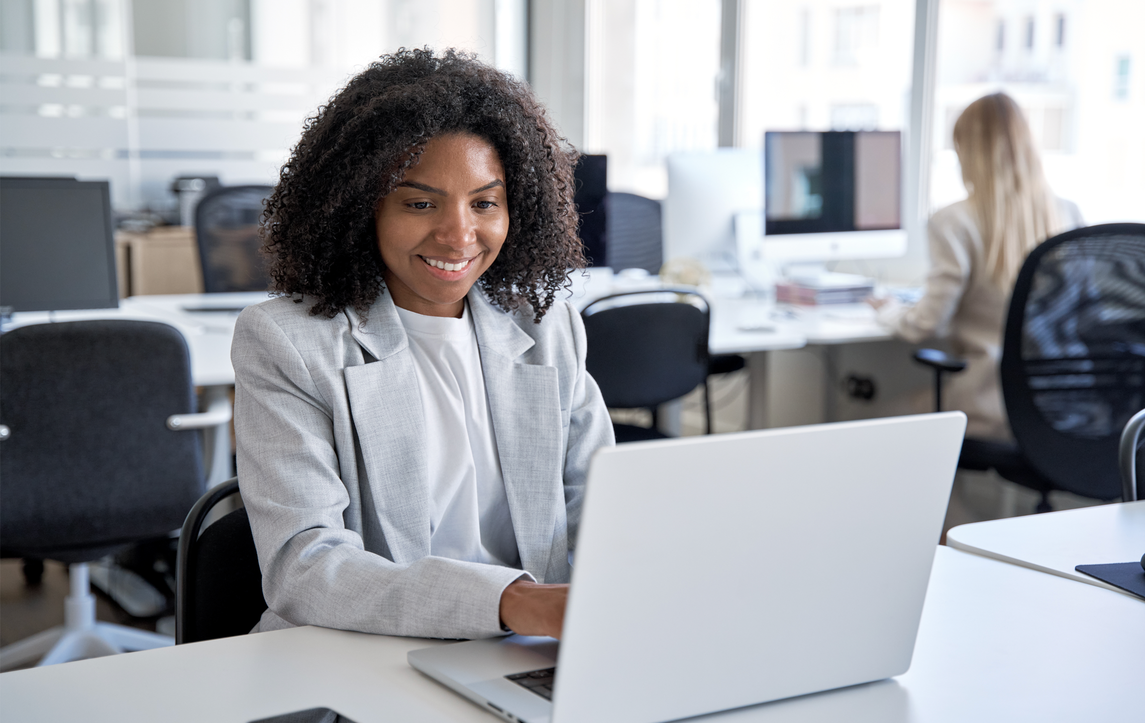 An SAP Concur Solutions user, Amanda, sits at a desk typing on a laptop