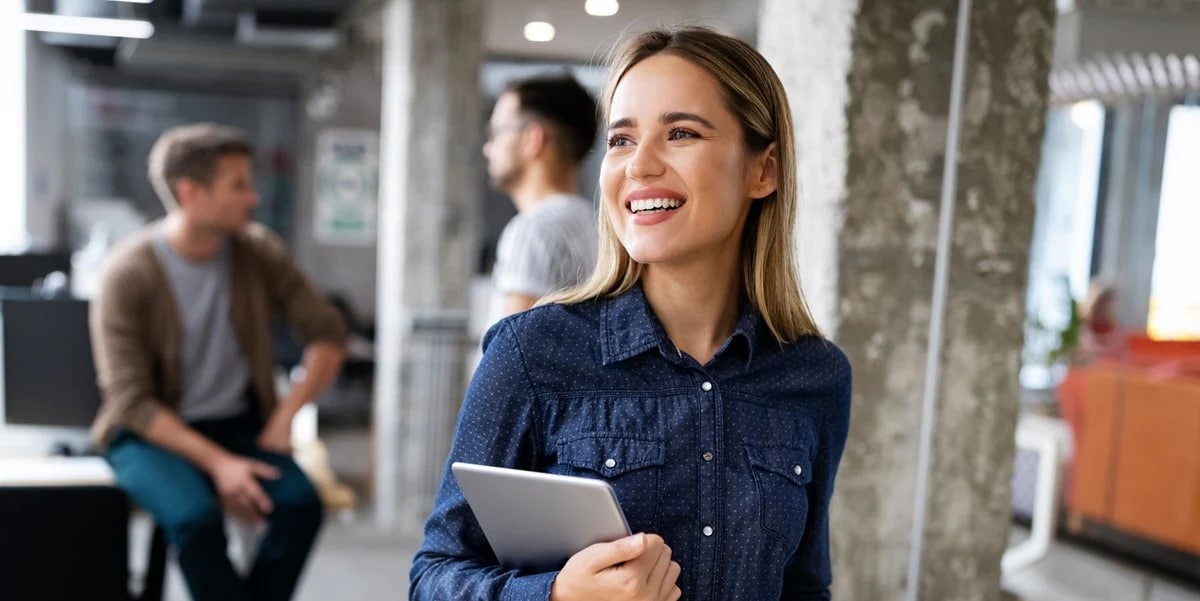 Woman in office smiling and holding tablet