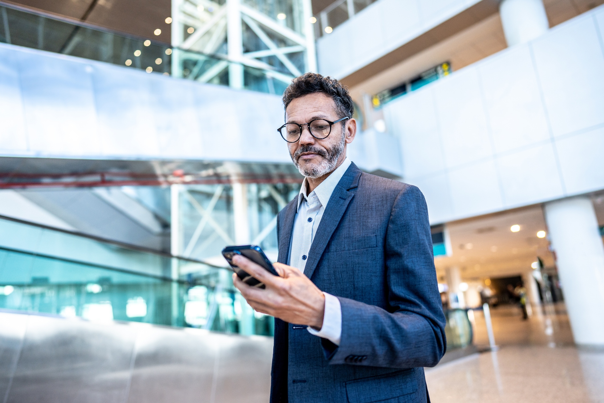 An SAP Concur Solutions user, Michael, stands in an airport holding a cellphone